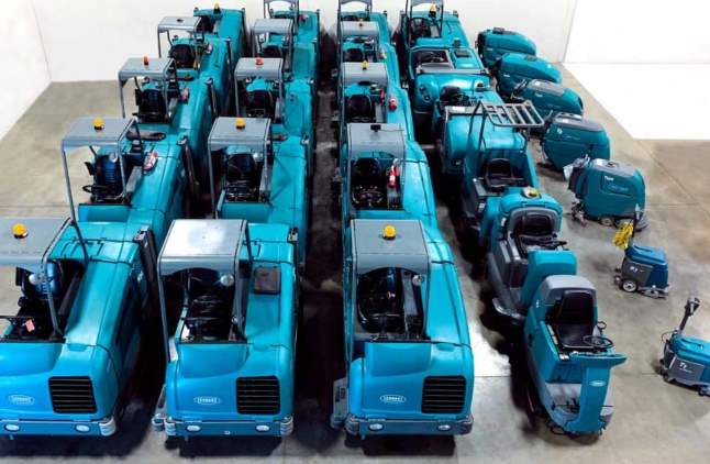 Tennant floor scrubber rental machines lined up on warehouse floor