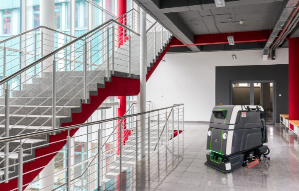 Robotic floor scrubber cleaning tile floor in commercial office space