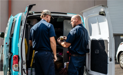 two floor scrubber service technicians next to van