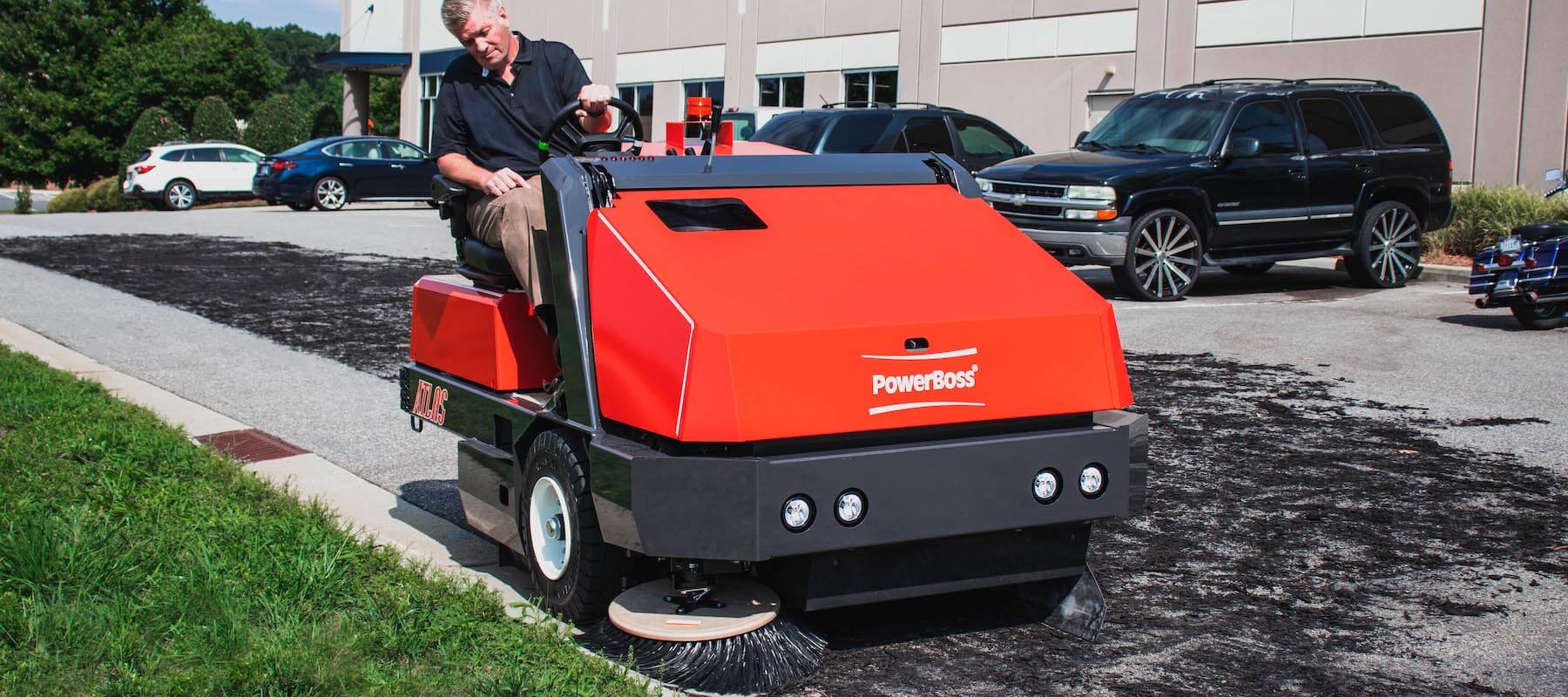 technician cleaning a parking lot with a powerboss atlas floor sweeper