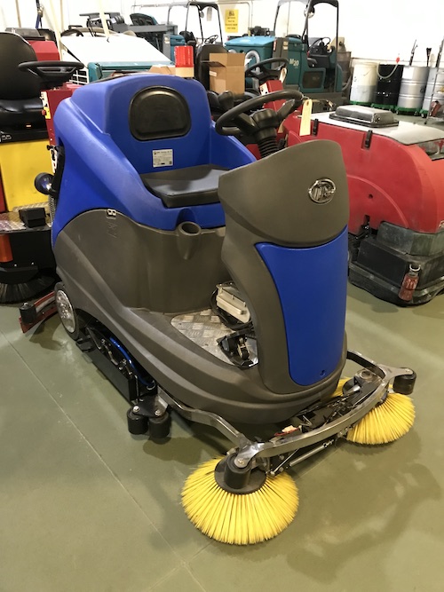 cheap rider floor scrubber sitting in warehouse next to other floor cleaning machines