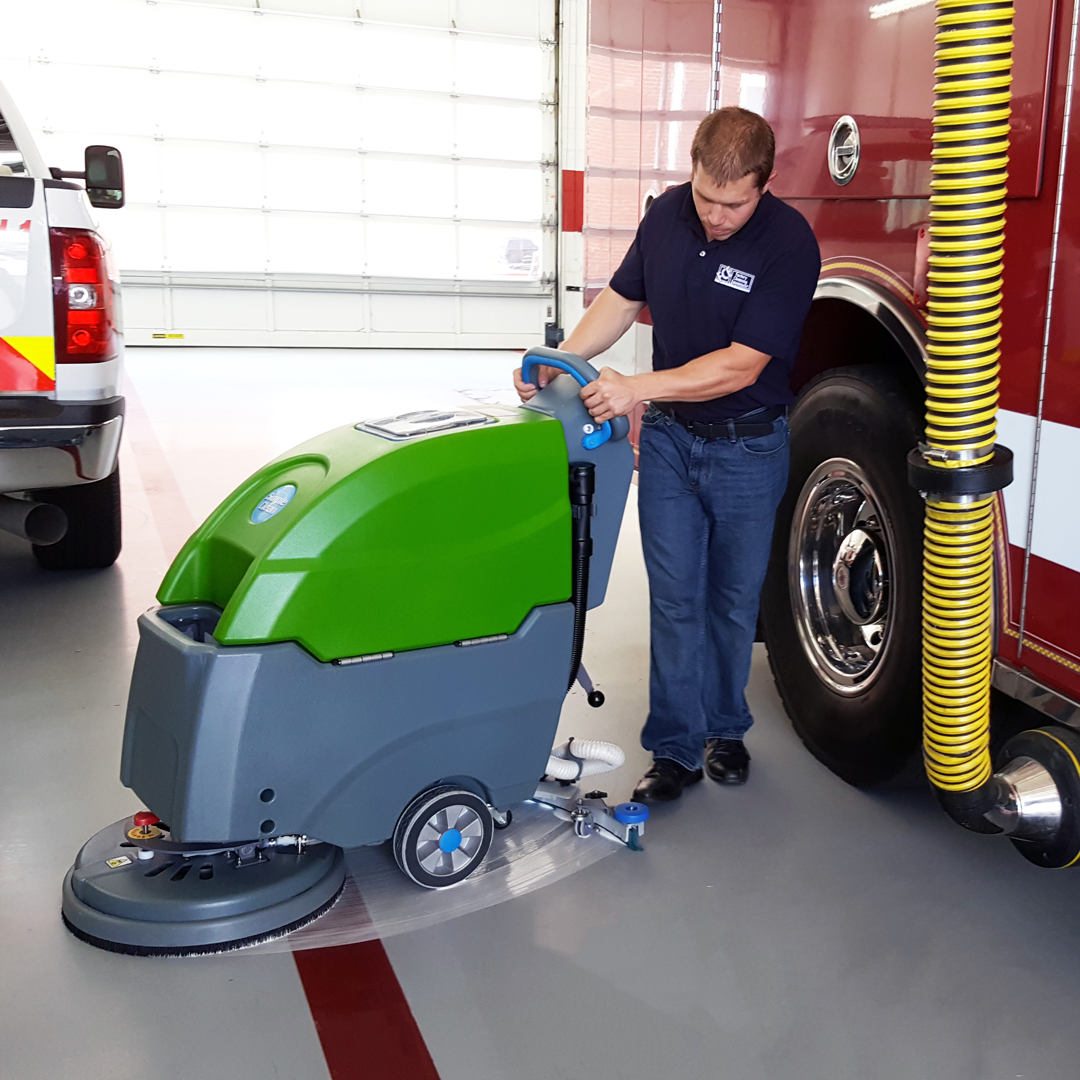 FCE technician demonstrating cleaning path of simple green scrubber next to a firetruck