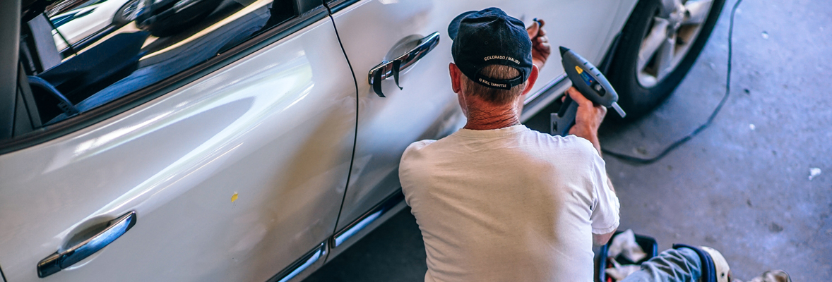 worker fixing car door in an automotive shop