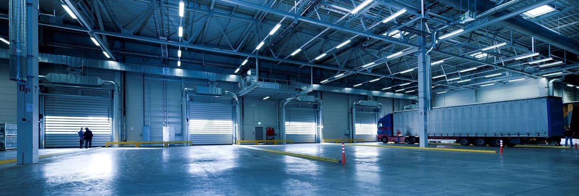 partially empty distribution center with concrete floor and trucked parked at door