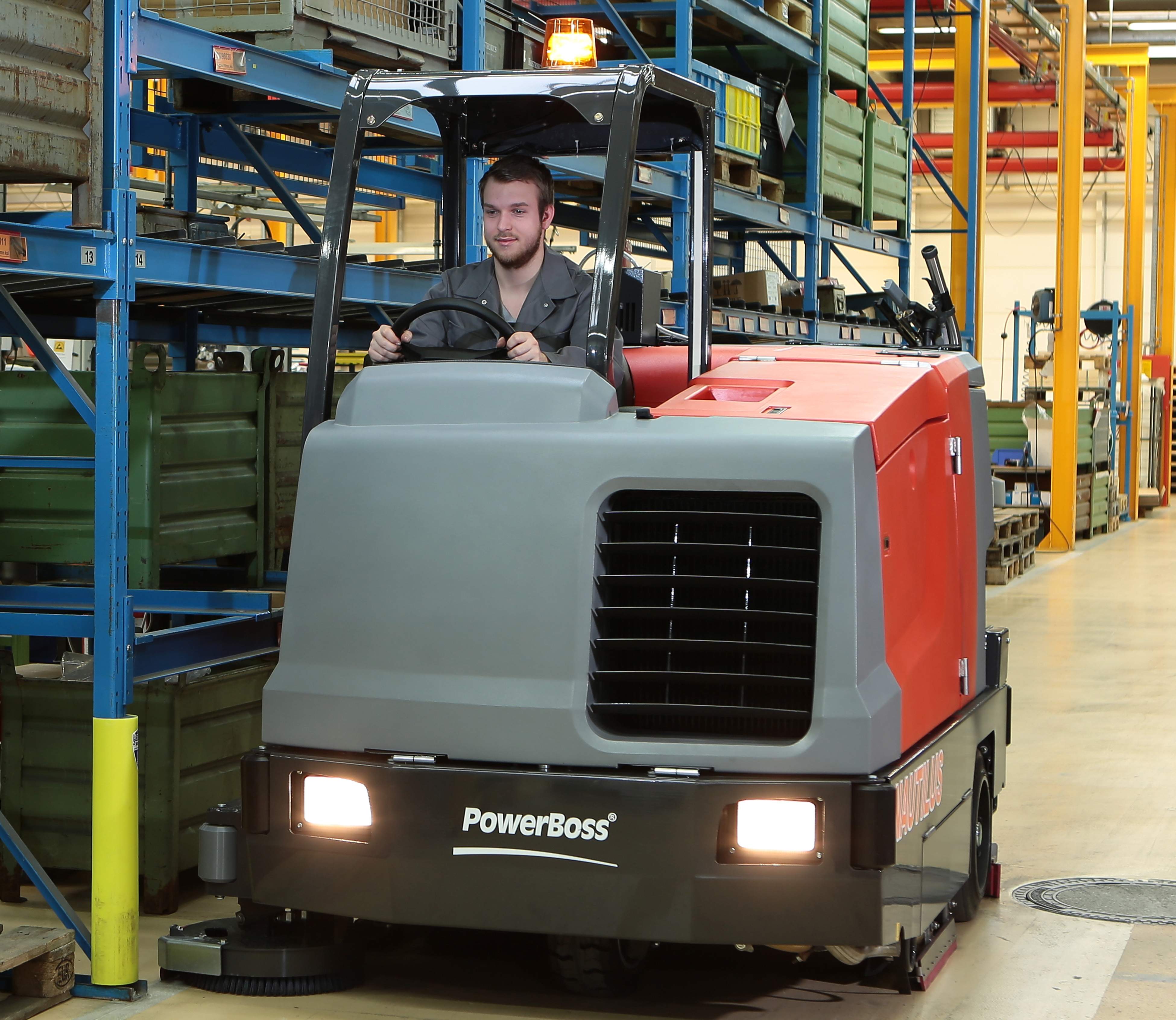 worker driving powerboss nautilus industrial rider floor scrubber in warehouse