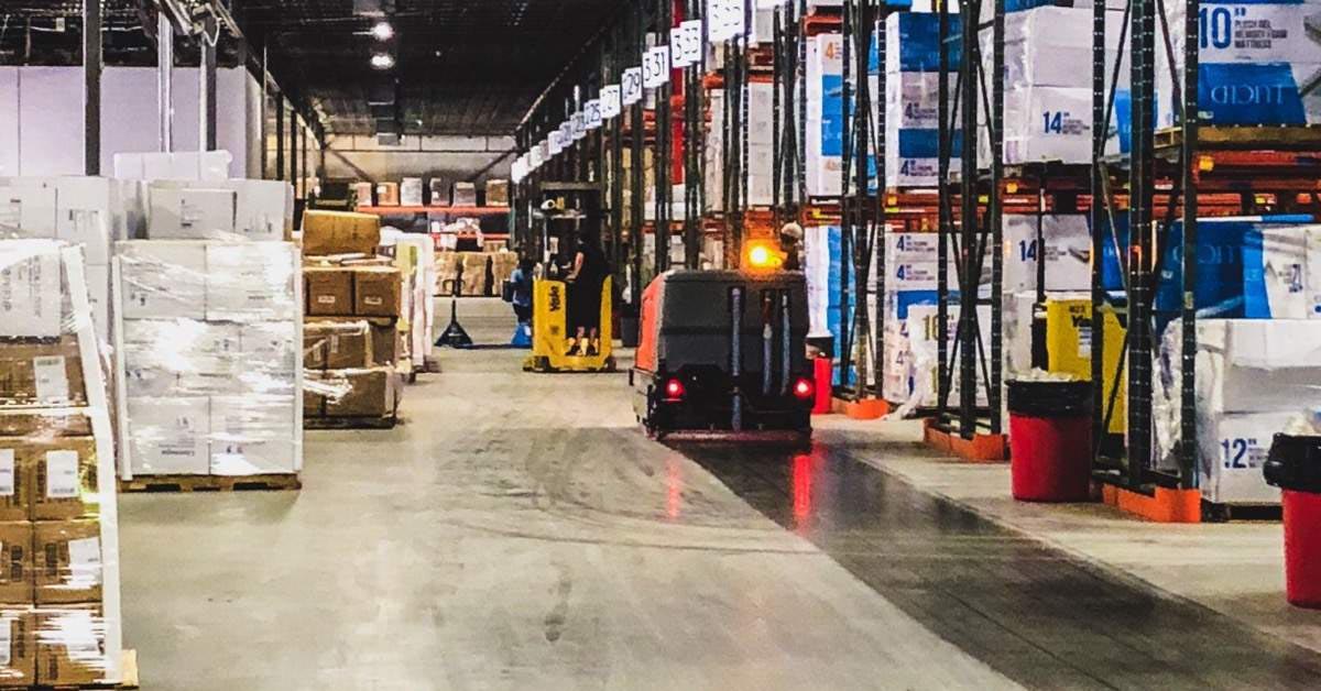 floor scrubber cleaning coated warehouse floor between shelves