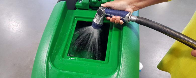 hand using hose to fill a floor scrubber recovery tank