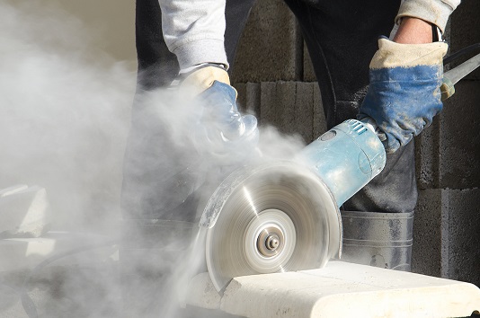 hands using ngled grinder and creating silica dust