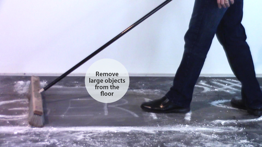 Person removing large objects from a gym mat with a broom