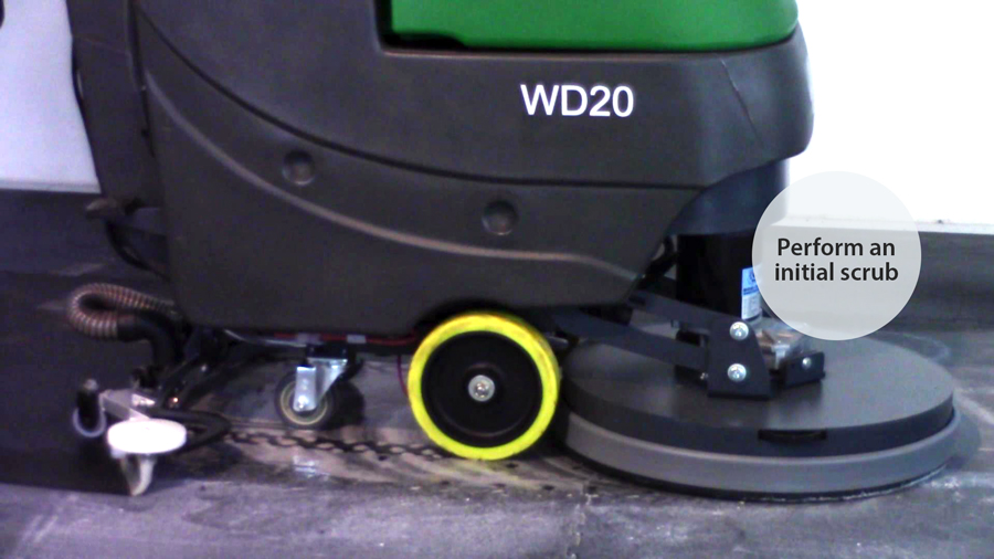 Industrial floor scrubber performing an initial cleaning of a gym mat